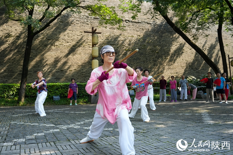 市民在西安城墻下的環(huán)城公園內(nèi)練習(xí)龍形鞭桿。李欣宇 攝